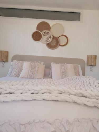 un lit blanc avec des oreillers et des chapeaux sur le mur dans l'établissement La parenthèse, à Béthisy-Saint-Pierre