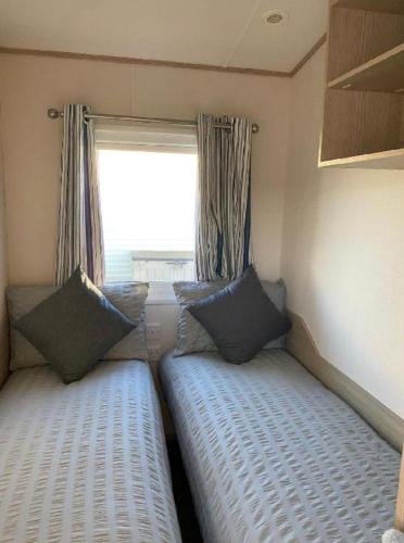 two beds in a small room with a window at Caravan - 3 Bedrooms, Sleeps 8 in Rhyl