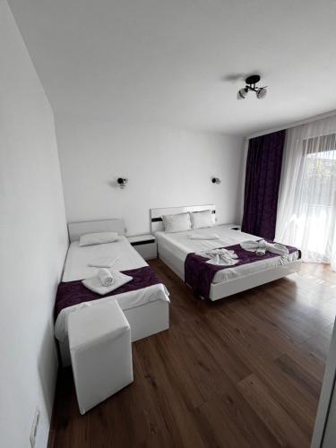 two beds in a room with wooden floors at Vila Elegance in Costinesti