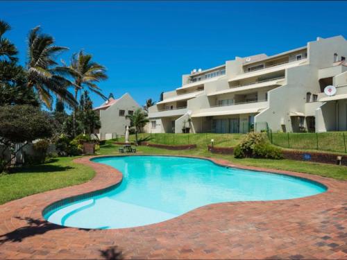 a swimming pool in front of a building at Beachfront Apartment Shakas Rock - Martinique, Pool, Ocean Views in Ballito