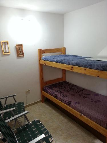 een slaapkamer met 2 stapelbedden en een stoel bij MaJoMi Toninas in Las Toninas