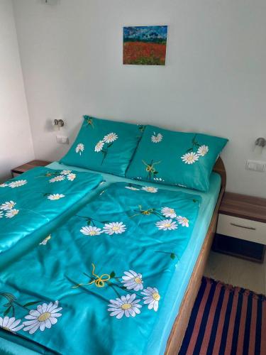 a bed with blue sheets with flowers on it at Apartman Anton in Stara Baška