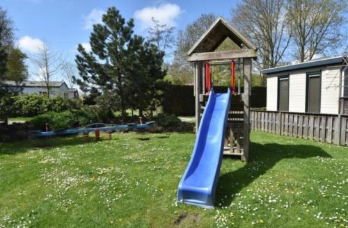 a playground with a slide in a yard at Mooi chalet in havenplaatsje op fietsafstand van het strand bij Ouddorp in Goedereede