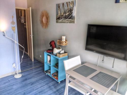 a living room with a flat screen tv and a table at Appartement vue mer et plage Saint-Aubin-Sur-Mer Normandie in Saint-Aubin-sur-Mer
