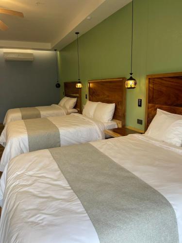 a hotel room with three beds with white sheets at Hotel Mi Linda Tierra in Quesada