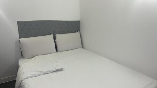 un lit avec des draps blancs et des oreillers dans une chambre dans l'établissement Studio Relax proche de Paris et Aéroport, à Vitry-sur-Seine