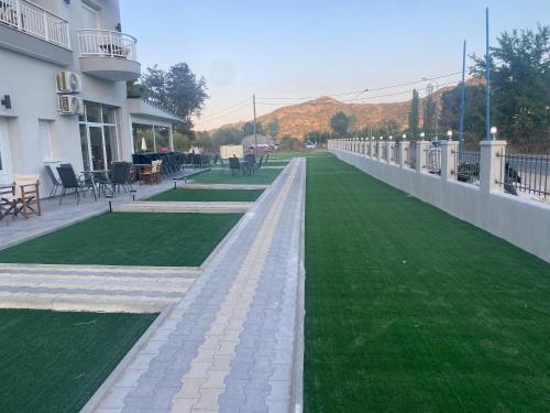 a long walkway with green grass next to a building at VSP RENT ROOMS FUeGO in Sikia