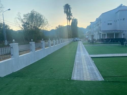 a long white wall with a green field next to a building at BSP RENT ROOMs in Paralia Sikias