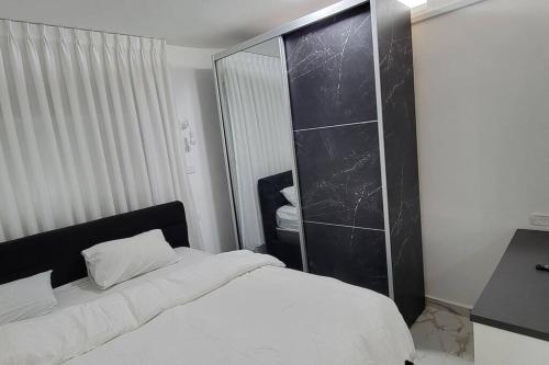 a bedroom with a white bed and a large mirror at Modern Apartment in Ramat Gan Next to Sheba in Ramat Gan