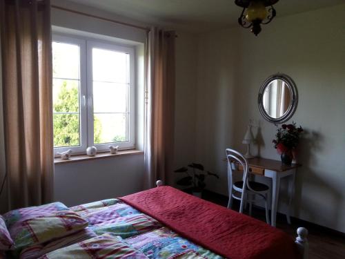 a bedroom with a bed and a table and a window at Wiejska Chata in Szwalk