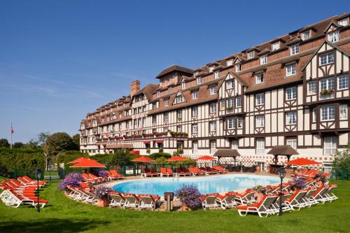 ein großes Gebäude mit einem Pool davor in der Unterkunft Hôtel Barrière L'Hôtel du Golf in Deauville