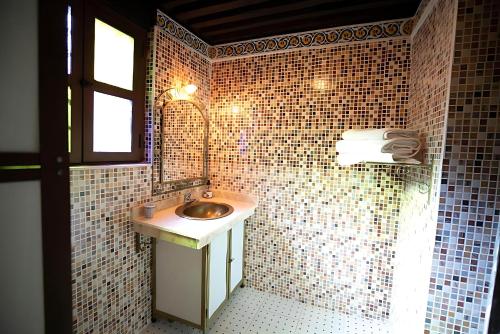 a bathroom with a sink and a tiled wall at Riad Mounana fez luxurious palace & spa in Fès