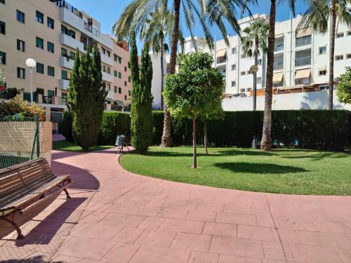 a park with a bench and palm trees and buildings at Habitación doble con baño privado, Desayuno y piscina in Alboraya