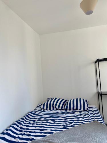 un lit avec un oreiller rayé bleu et blanc dans l'établissement Chambre d'hôtes équipée et neuve, à Drancy