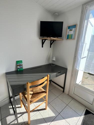 a black desk with a chair and a television on a wall at Chez Laurie et Xavier studio 3 in Mignaloux-Beauvoir