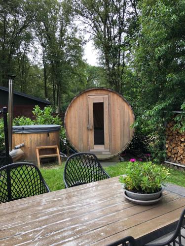 a wooden table with chairs and a large wooden tub at Vakantiewoning Mystiek in Zutendaal