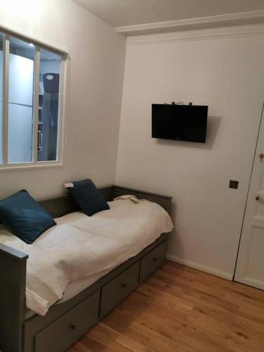 une chambre avec un lit avec une télévision au mur dans l'établissement Appartement près de Rolland Garros et le parc des Princes, à Paris