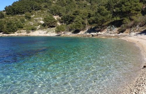 a beach with clear blue water and a rocky shore at Taverna -Sunce- with jacuzzi in Vis