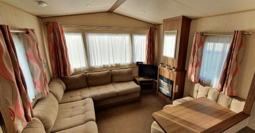 ein Wohnzimmer mit einer Couch und einem Tisch in einem Zimmer in der Unterkunft Oxley Retreat, West Sands, Seal Bay Resort in Selsey