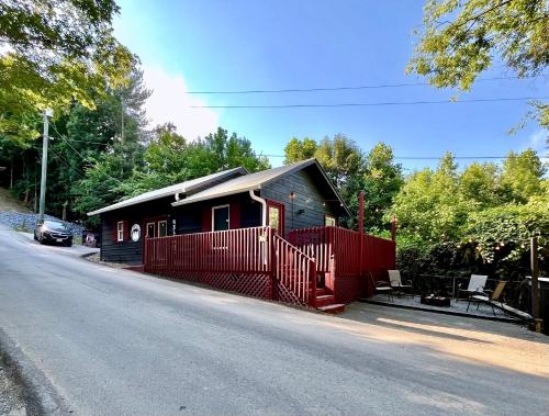 a small house with a red fence next to a road at Smores Retreat - Minutes from PF Parkway! Hot tub and fire pit! in Pigeon Forge