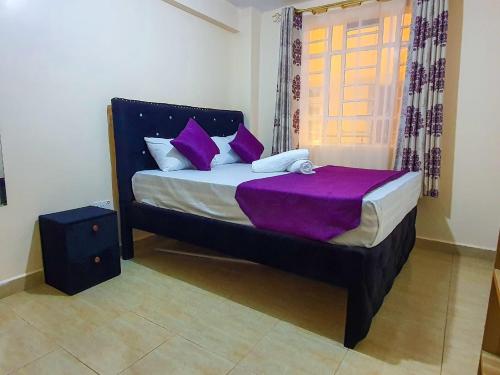 a bedroom with a bed with purple sheets and a window at Stunning one bedroom unit in Ruiru with free parking in Ruiru