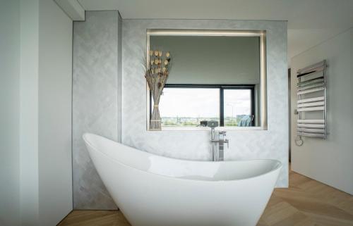 a white tub in a bathroom with a mirror at MARVEL apartamentai in Kaunas