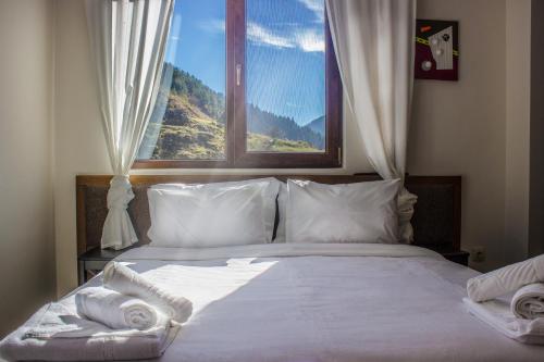 a bedroom with a bed with white sheets and a window at Trigrad Hotel in Trigrad
