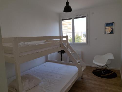 a bedroom with two bunk beds and a chair at Appartement traversant 2 chambres in Ajaccio