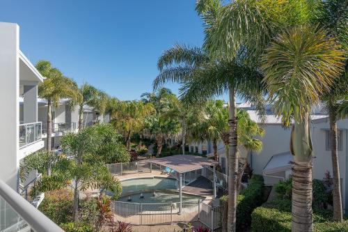an aerial view of a resort with a swimming pool and palm trees at Beach Life at Coolum in Coolum Beach