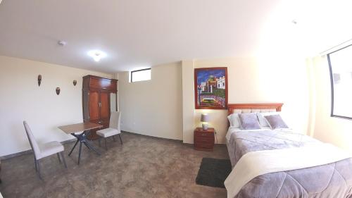 a bedroom with two beds and a desk in it at Hotel Suite Central Park Tababela in Quito