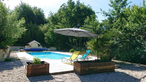 - une piscine avec un parasol et deux chaises à côté dans l'établissement Domaine Casquil, à Panjas