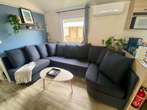 un salon avec un canapé bleu et une table dans l'établissement MH 639 6 à 7 personnes Tout équipé Climatisé Camping 4 étoiles Le Bois Dormant, à Saint-Jean-de-Monts