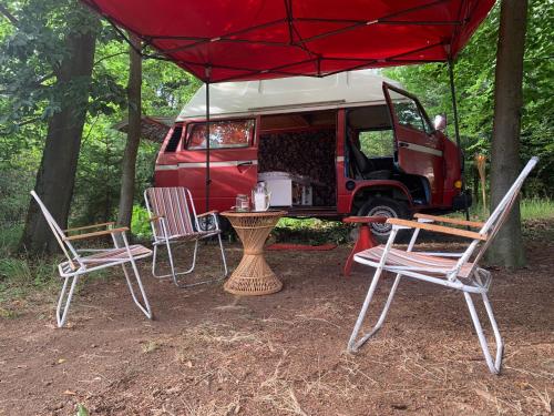 a table and chairs and a red van with a tent at Nad rybníkem Hnačov - rodinný rekreační areál in Hnačov