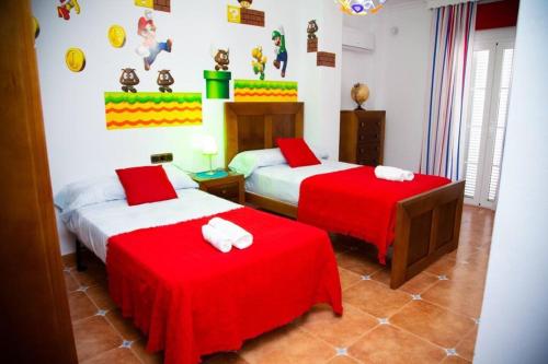 two beds in a room with red and white sheets at Villa Ana Todo Confort in Alora
