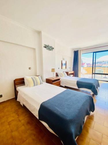 a hotel room with two beds and a window at Caparica Terrace Beach Apartment in Costa da Caparica
