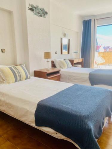 a hotel room with two beds and a window at Caparica Terrace Beach Apartment in Costa da Caparica