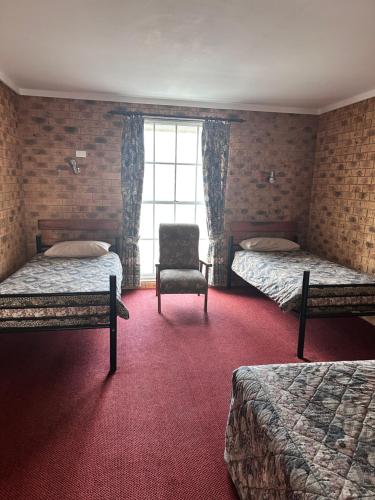 a hotel room with two beds and a chair at San Michele Adaminaby in Adaminaby