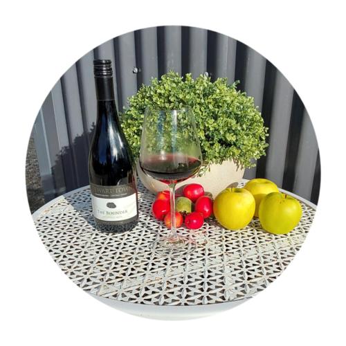 a bottle of wine and fruit on a table at Cosy Rural Retreat in Cromwell