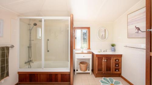 une salle de bain avec douche et lavabo dans l'établissement Cane Cutters Cottage, à Woombah