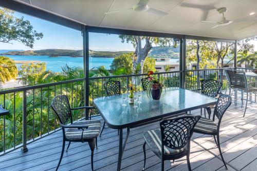 a table and chairs on a deck with a view of the water at Heliconia Grove - 3 bedroom - on Hamilton Island by HIHA in Hamilton Island