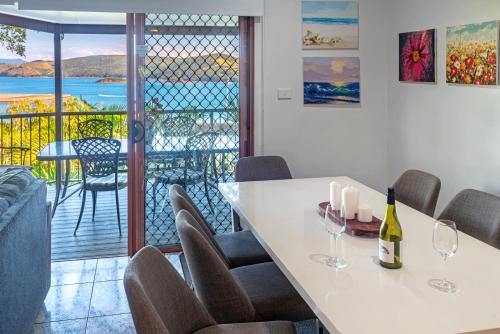 a dining room with a table and chairs and a balcony at Heliconia Grove - 3 bedroom - on Hamilton Island by HIHA in Hamilton Island