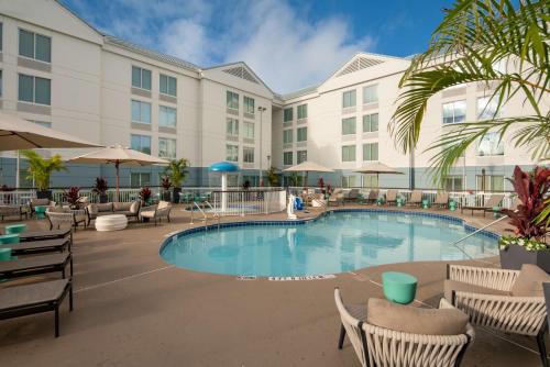 a pool at a hotel with chairs and umbrellas at Hilton Garden Inn Orlando Airport in Orlando