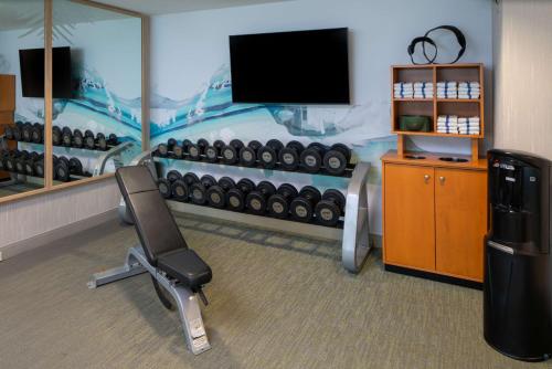 a room with a gym with a television and a chair at Hilton Garden Inn Orlando Airport in Orlando