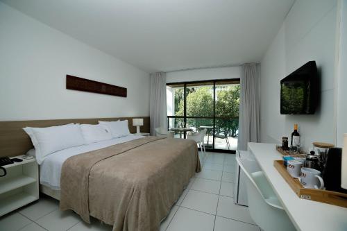 a hotel room with a bed and a balcony at Iloa Condo Supreme Hospedagens in Barra de São Miguel
