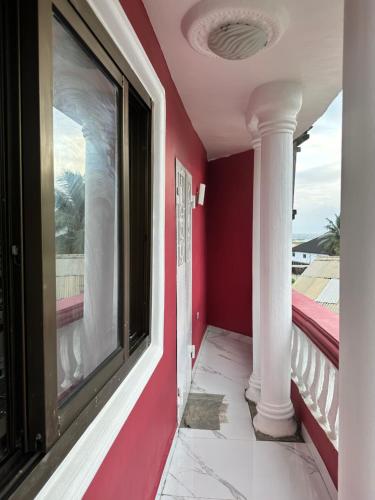 een balkon met rode muren en witte zuilen bij Costal Vibe Escapes in Monrovia