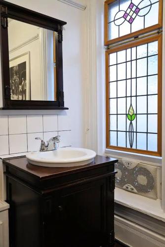a bathroom with a sink and a mirror and a window at Vancouver Hideaway Guesthouse in Vancouver