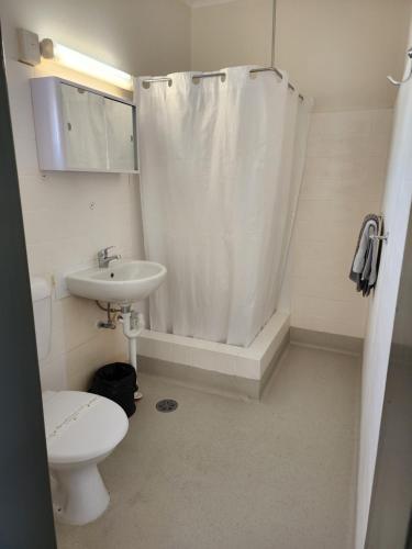 a bathroom with a toilet a sink and a shower at Inverell Motel in Inverell