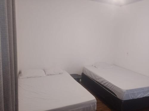 zwei Betten in einem Zimmer mit weißen Wänden in der Unterkunft Aurora dos Pireneus in Pirenópolis