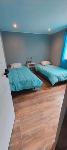 two beds in a room with a blue ceiling at Aoni Home in El Calafate