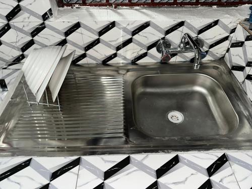 蒙罗维亚Coastal Vibe Escapes的厨房里设有不锈钢水槽,铺有黑白瓷砖